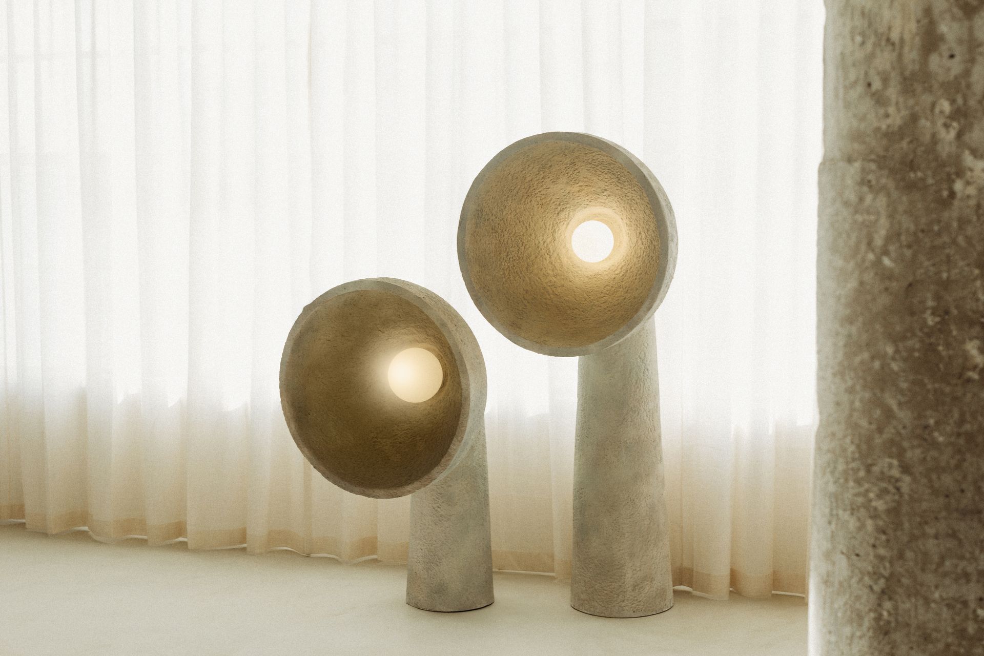 Two lamps are sitting next to each other in a room in front of a window.
