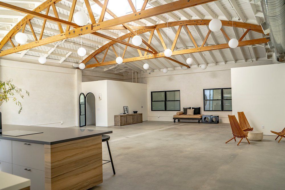 A large empty room with a wooden ceiling and a wooden table and chairs.