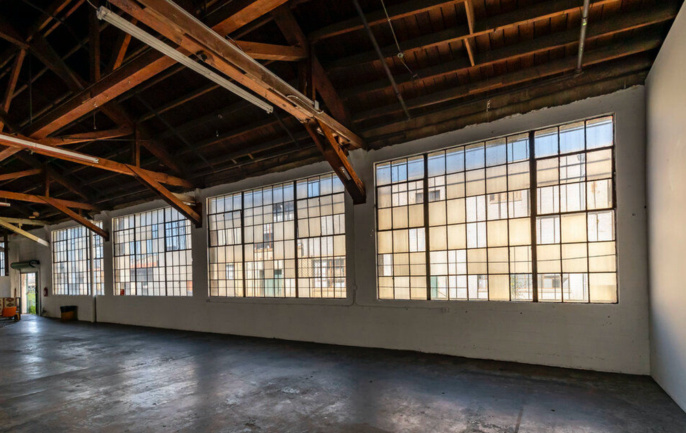 A large empty room with lots of windows and wooden beams.