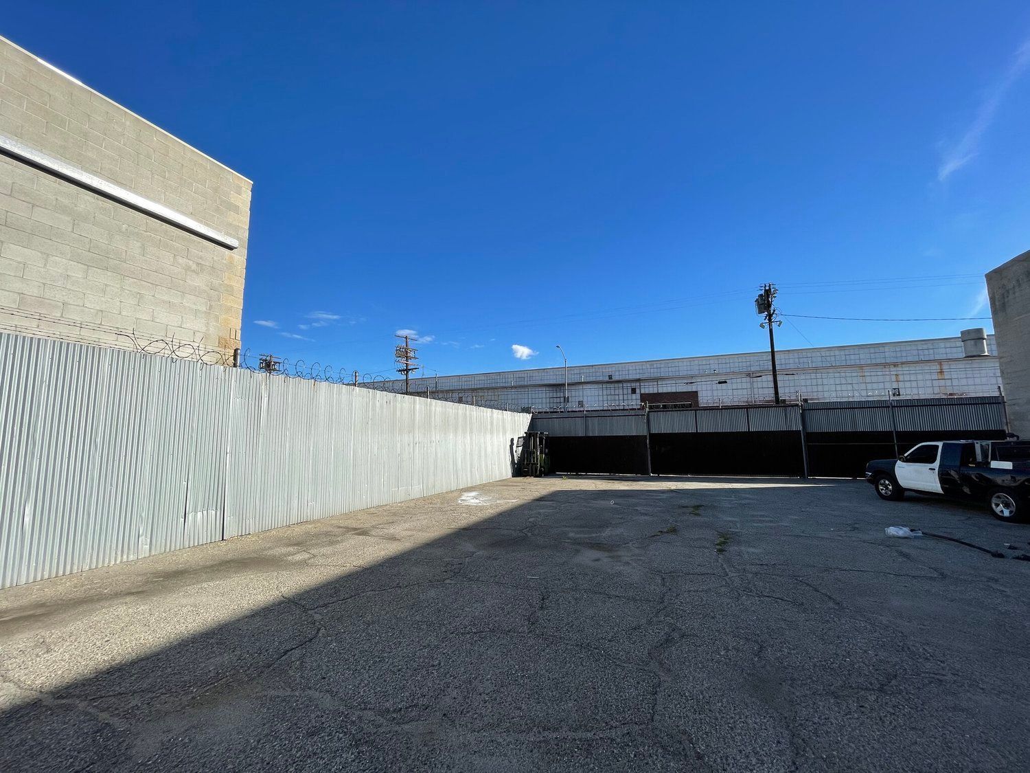 A parking lot with a fence and a building in the background.