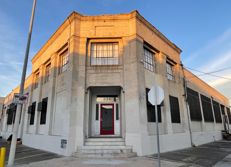 A large building with a red door is on the corner of a street.