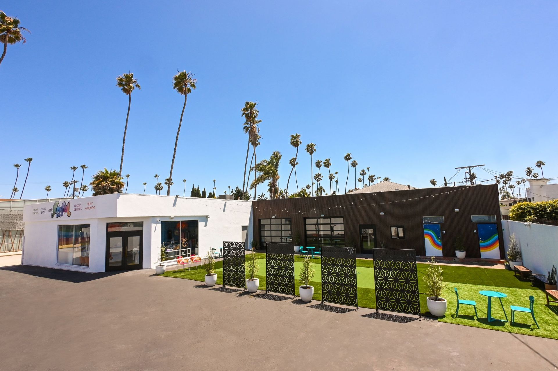 A white building with palm trees in the background
