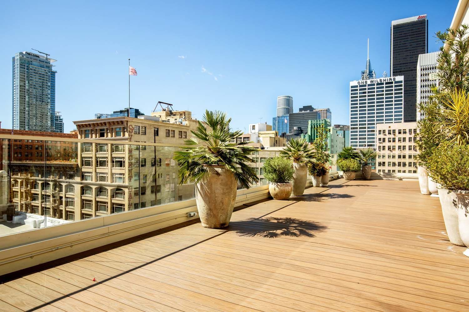 A balcony with lots of potted plants and a city skyline in the background