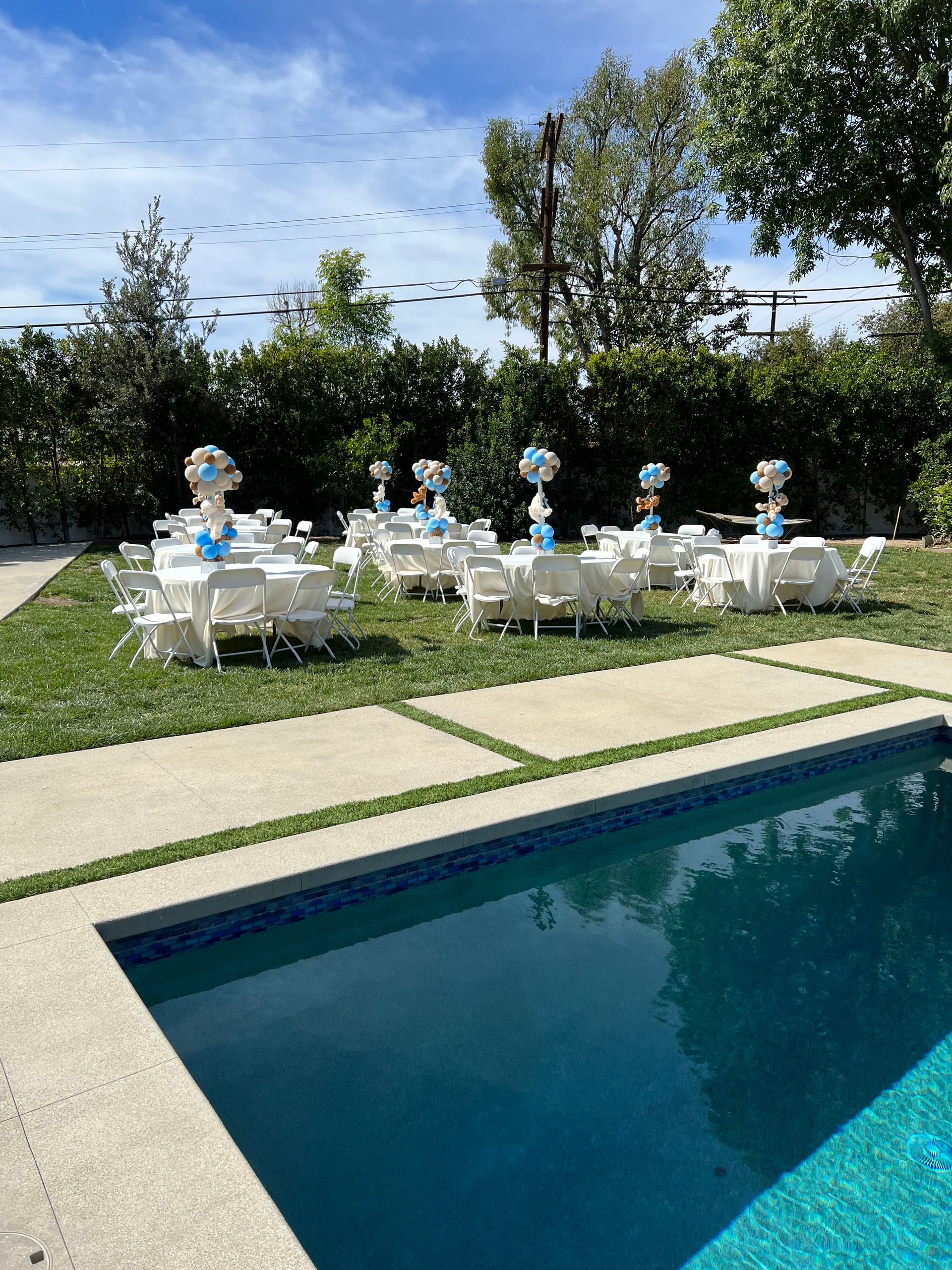 A swimming pool with tables and chairs set up in front of it.