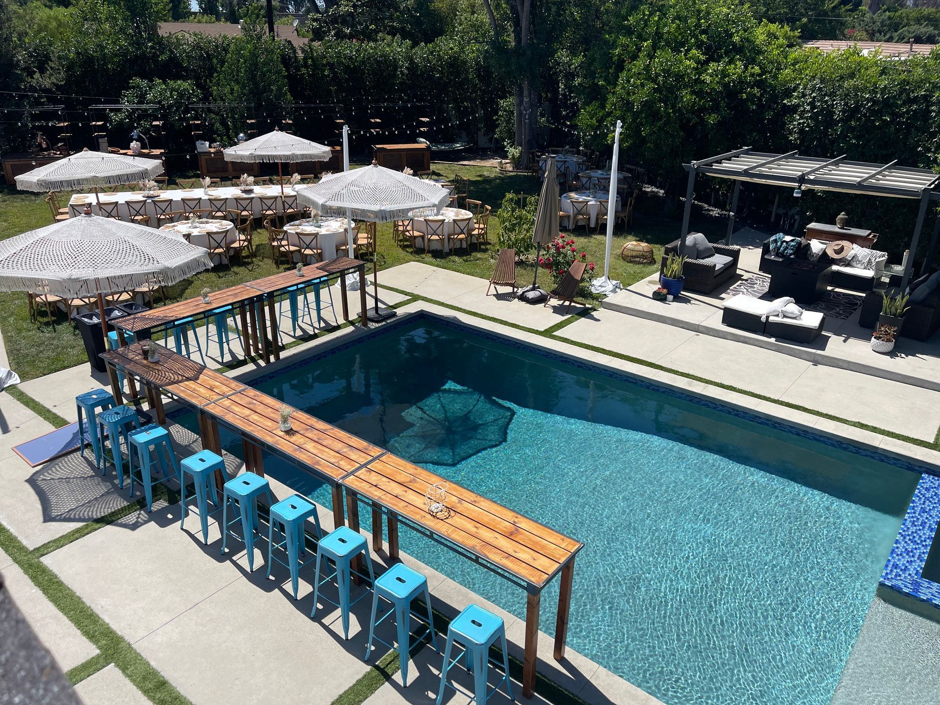 An aerial view of a large swimming pool with tables and chairs around it