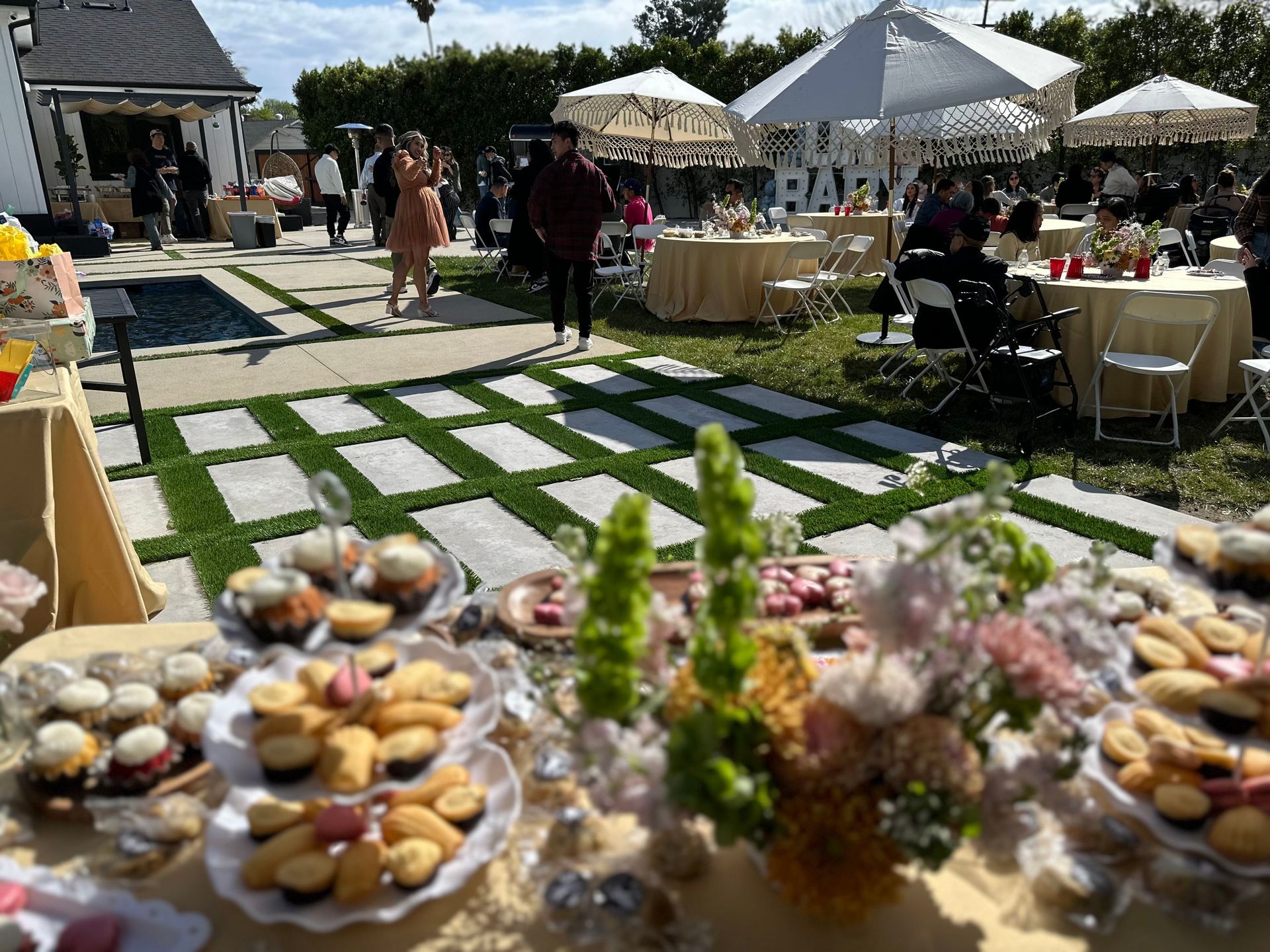 A table filled with cupcakes , cookies , and flowers at a party.
