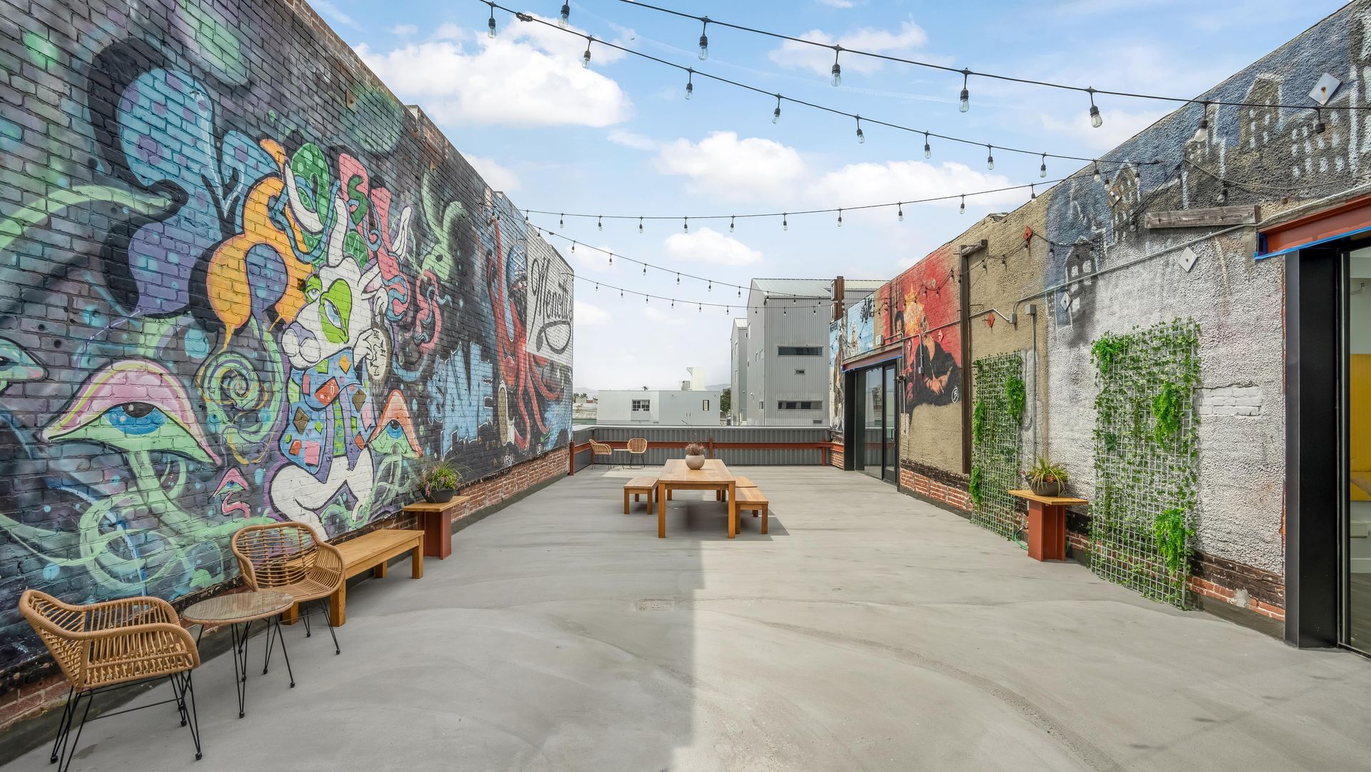 A patio with a table and chairs in front of a brick wall with graffiti on it.