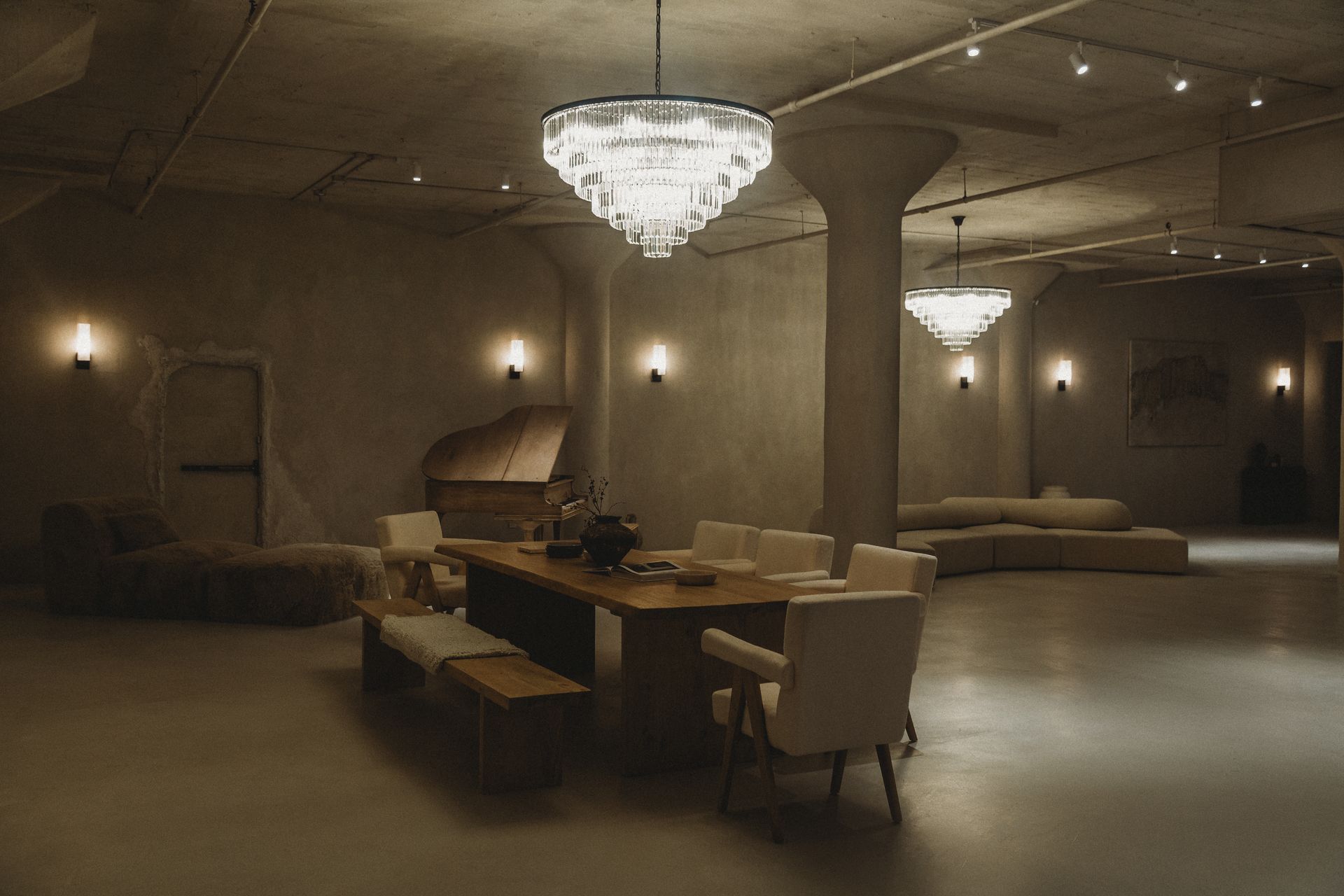 A large room with a table and chairs and a chandelier hanging from the ceiling