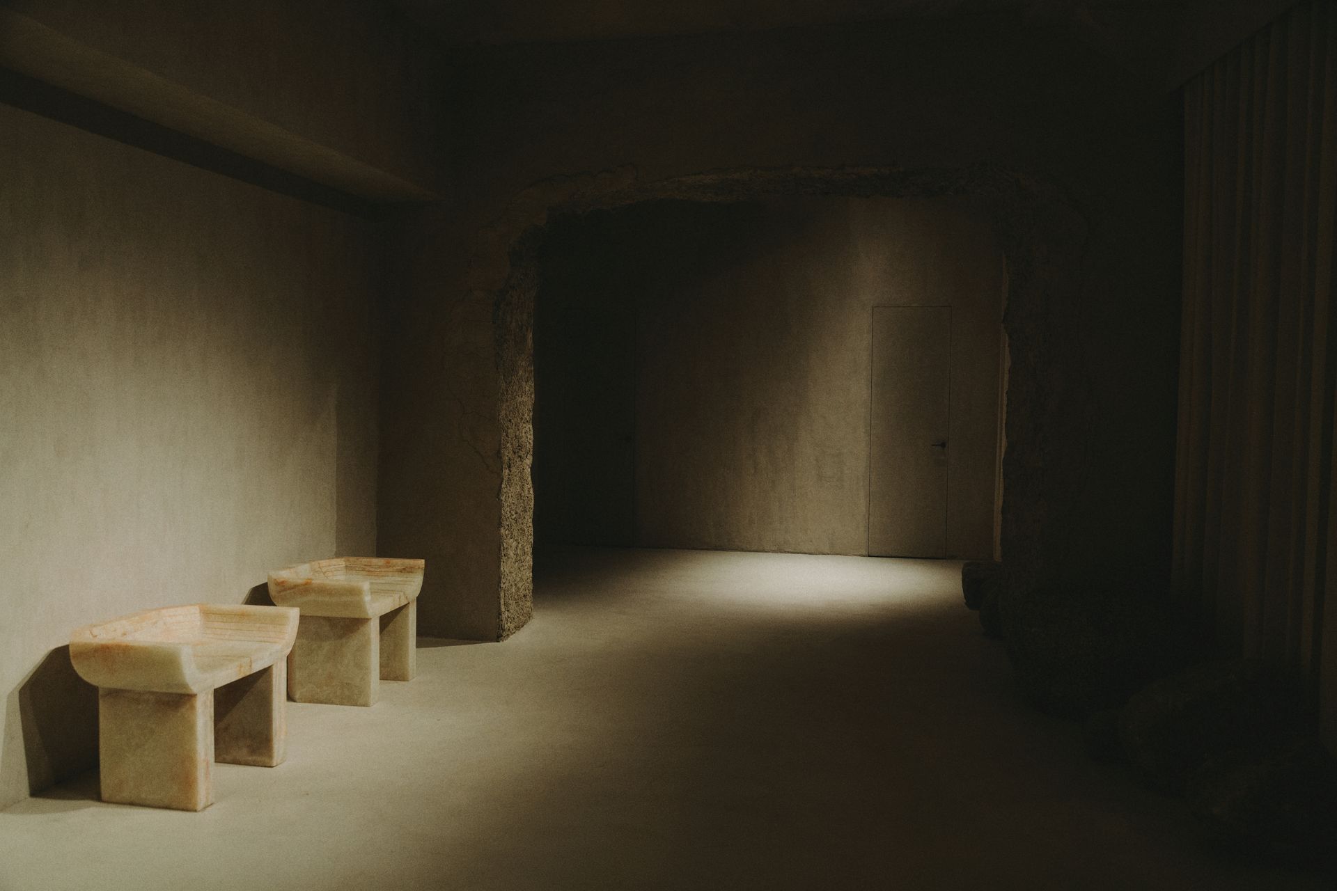 There are two benches in the middle of a dark hallway.