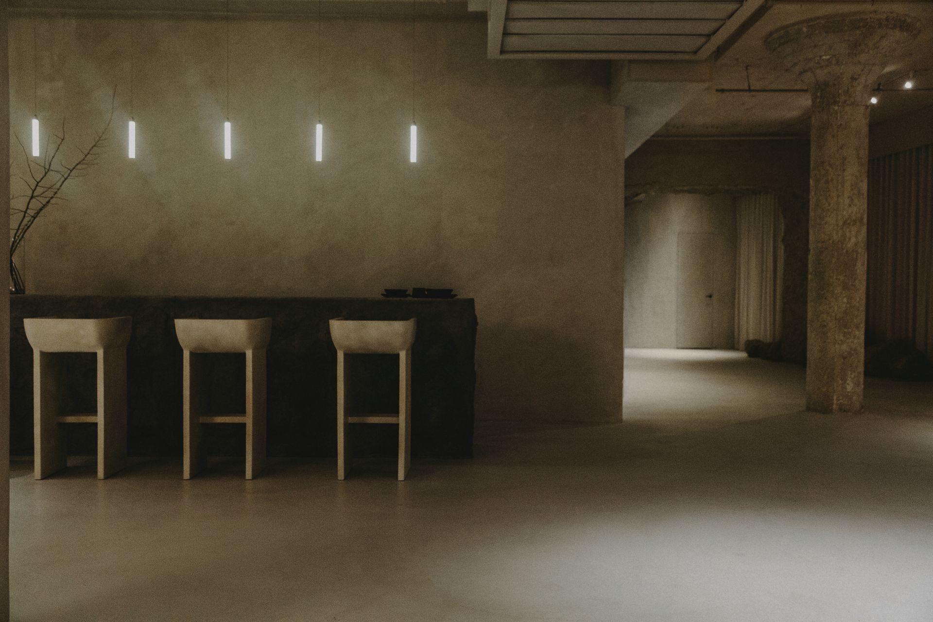 A row of bar stools are lined up in a dark room.