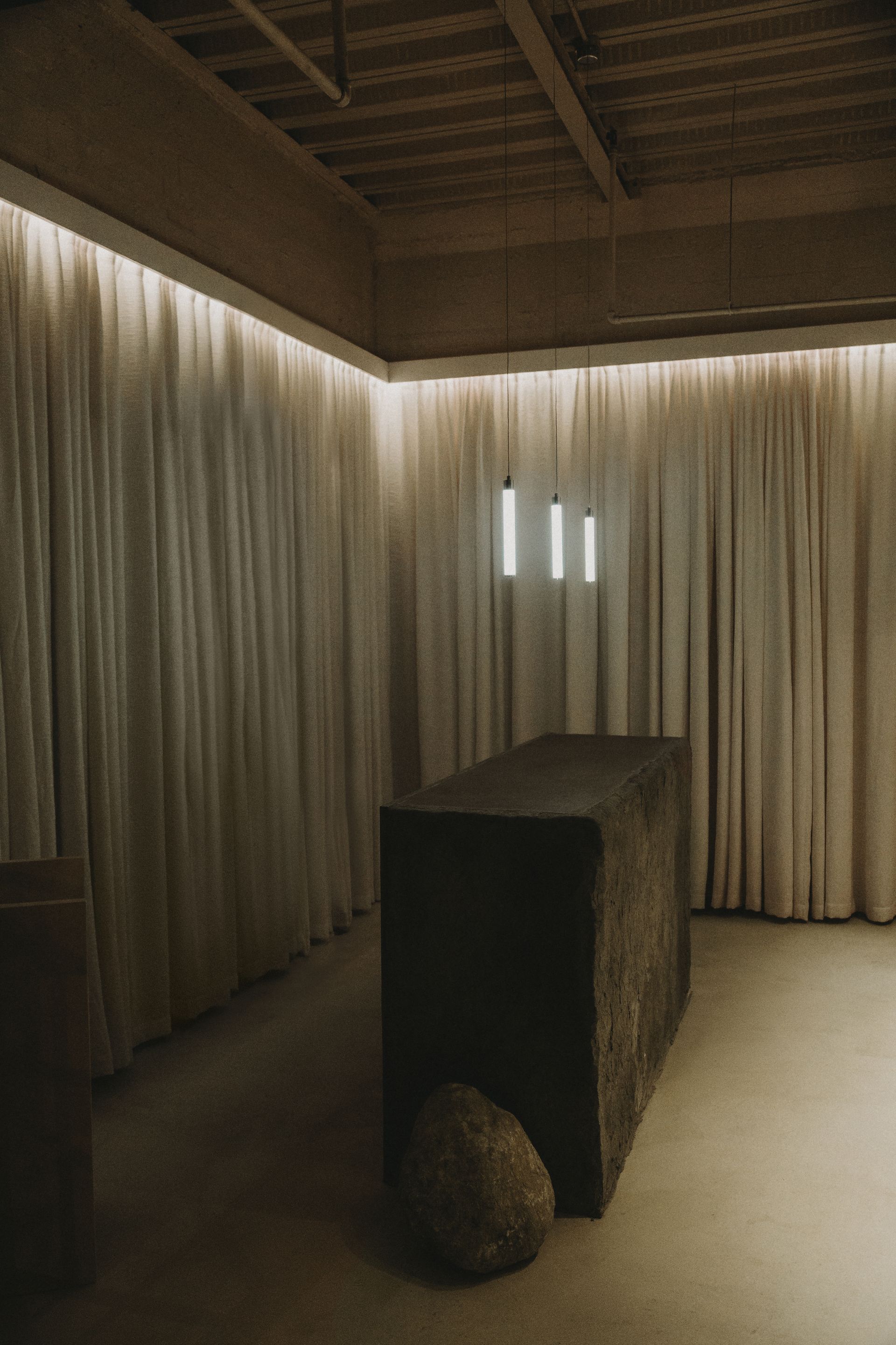 There is a table in the middle of the room with curtains hanging from the ceiling.