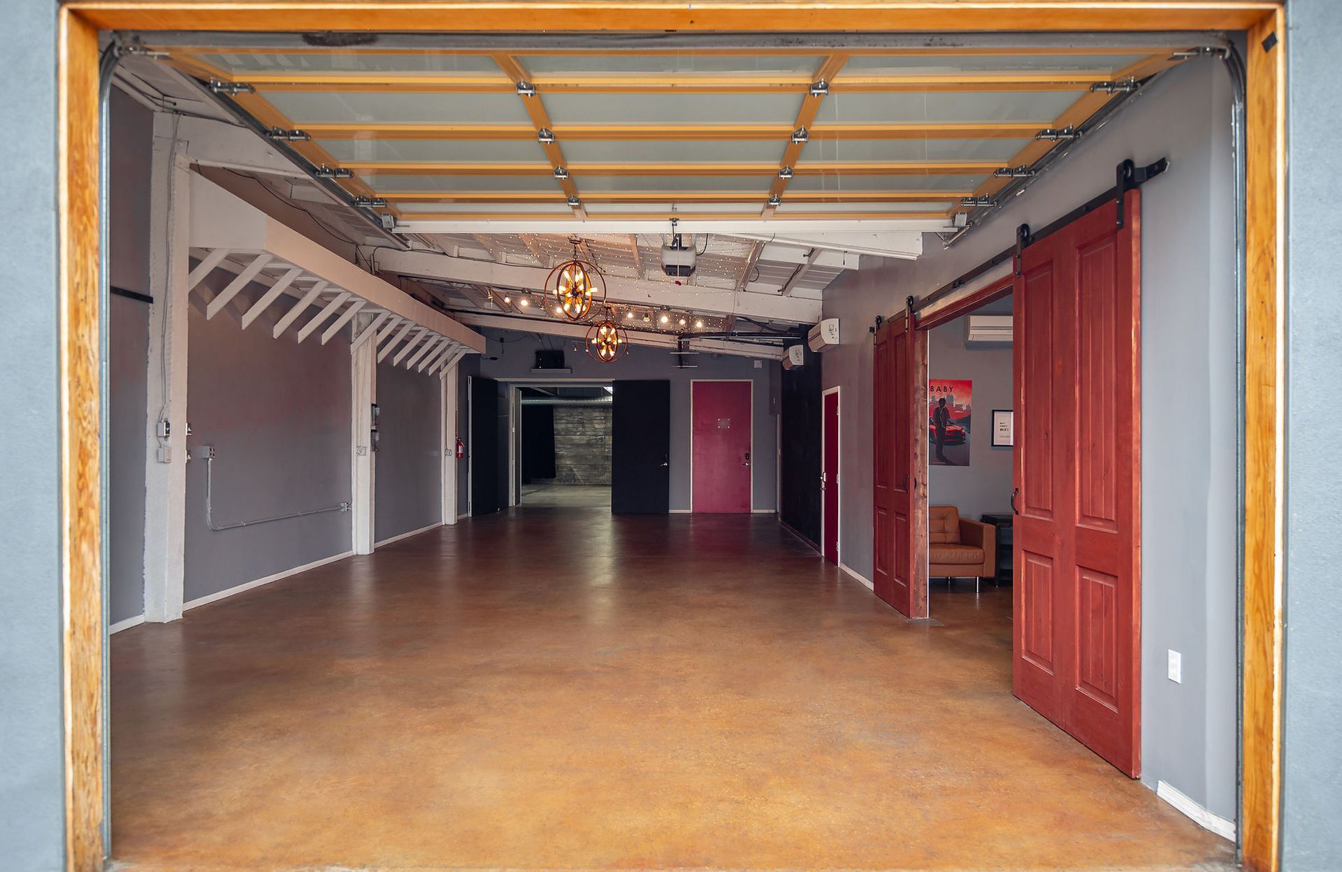 A large empty room with sliding barn doors and a chandelier hanging from the ceiling.