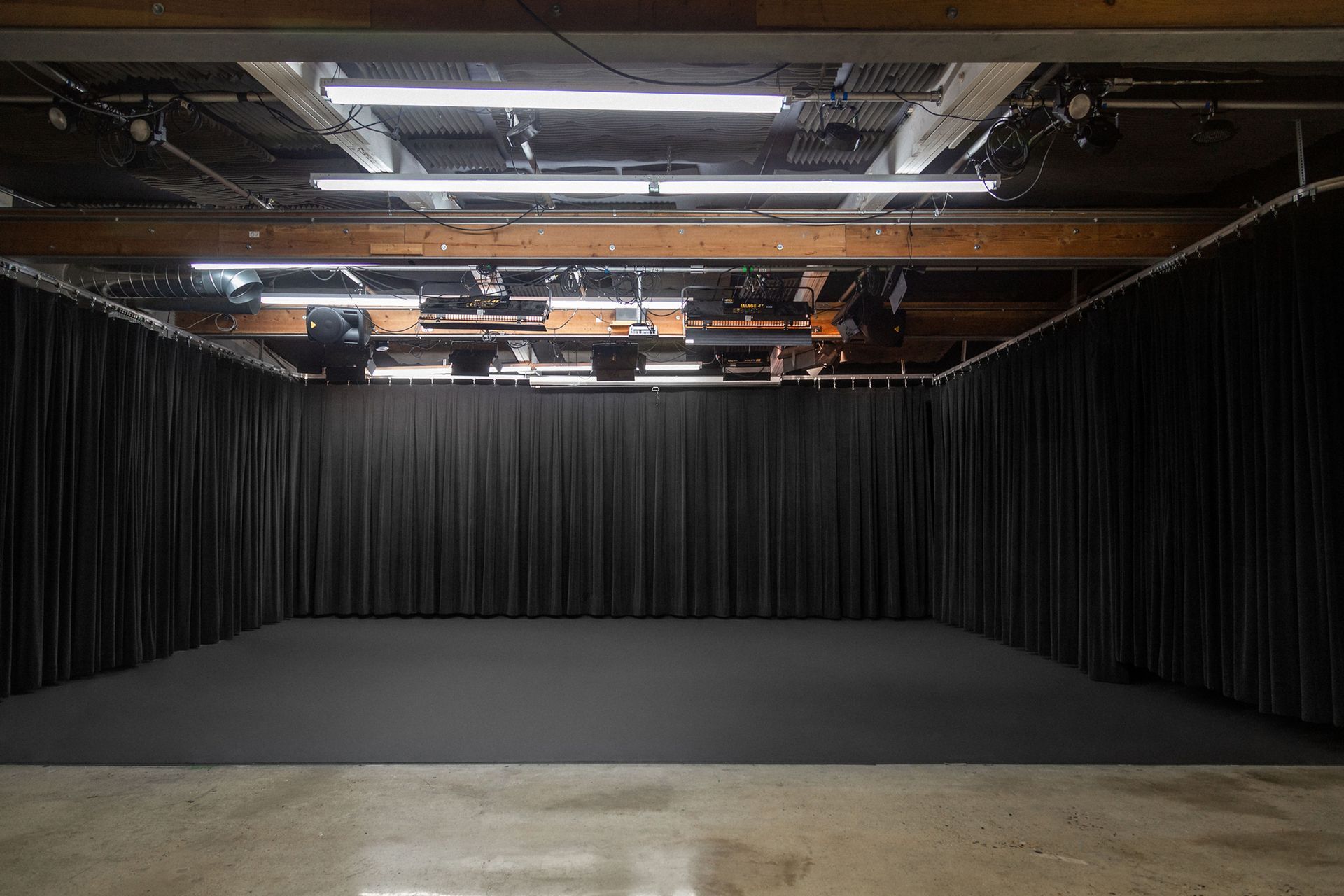 A large empty room with black curtains and lights on the ceiling