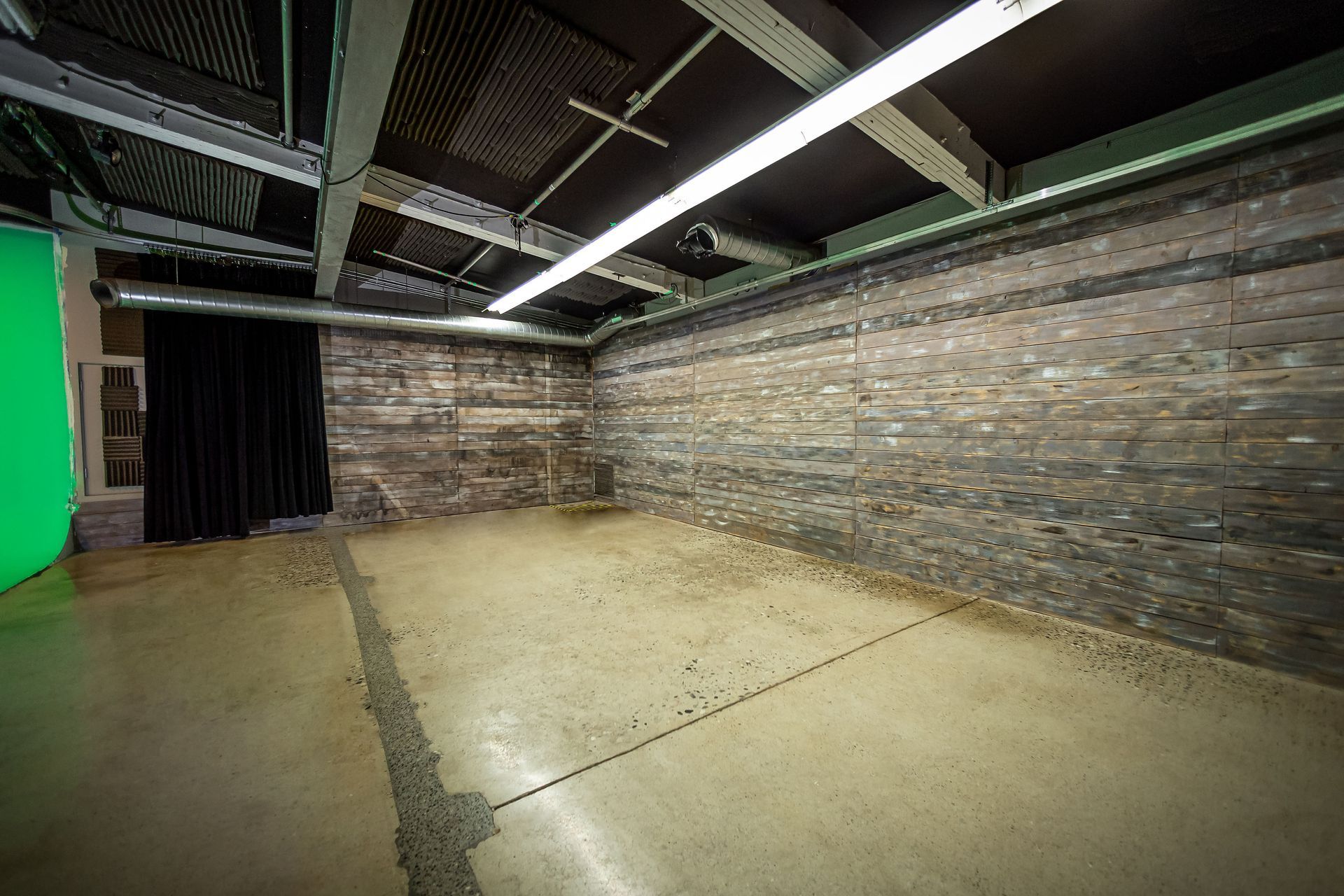 An empty room with a green screen and a brick wall.