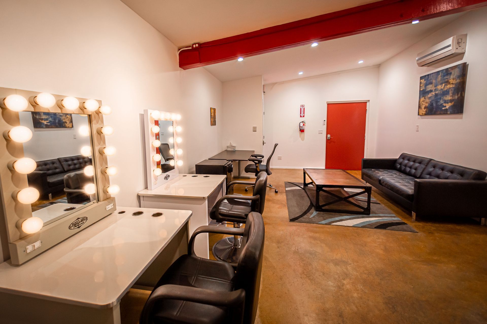 A room with a couch , chairs , tables and mirrors.