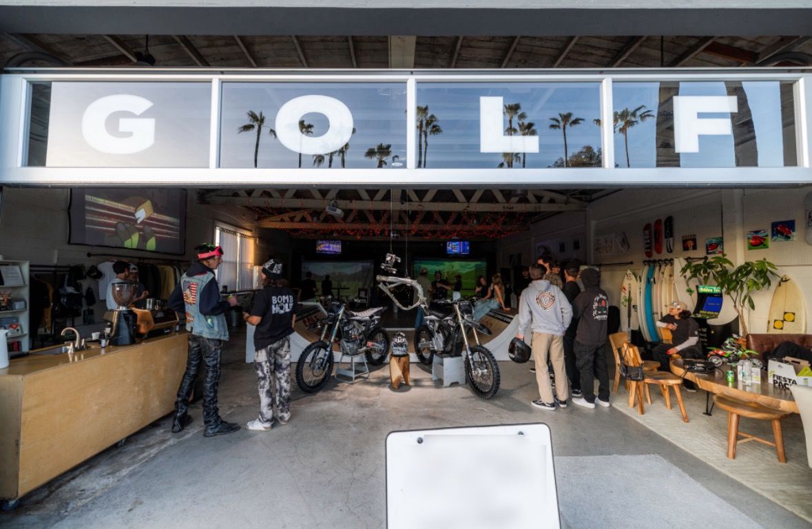 A group of people are standing in a garage under a sign that says golf.