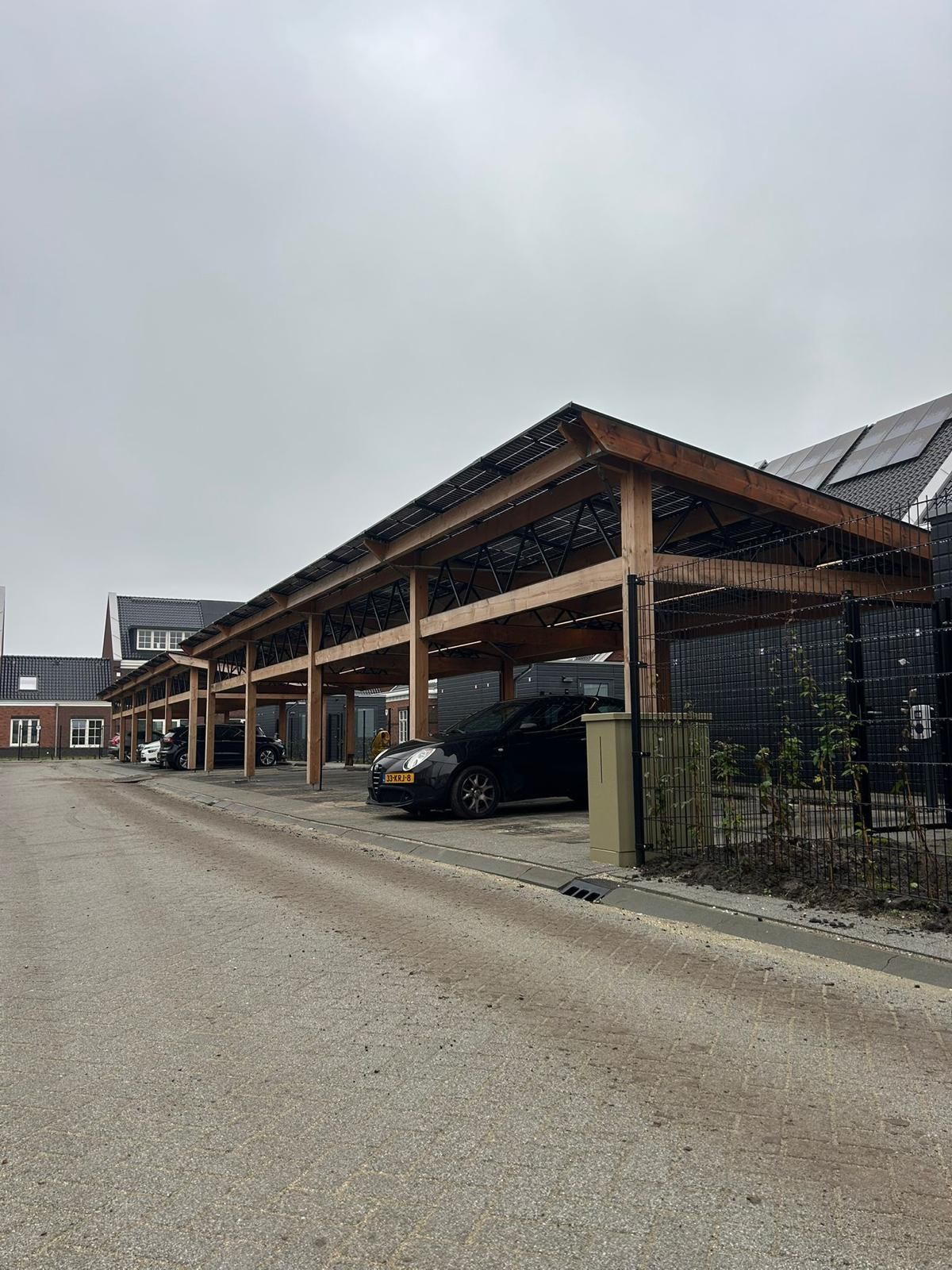 Iemand die een houten carport bouwt. Bewolkte lucht op de achtergrond.