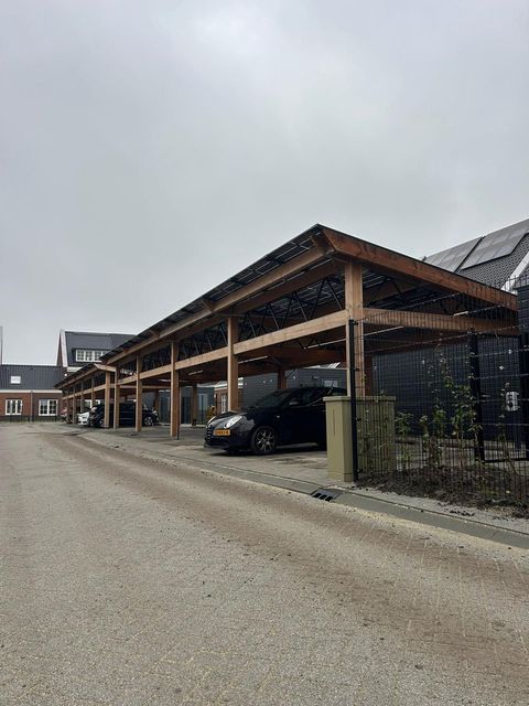 Iemand die een houten carport bouwt. Bewolkte lucht op de achtergrond.