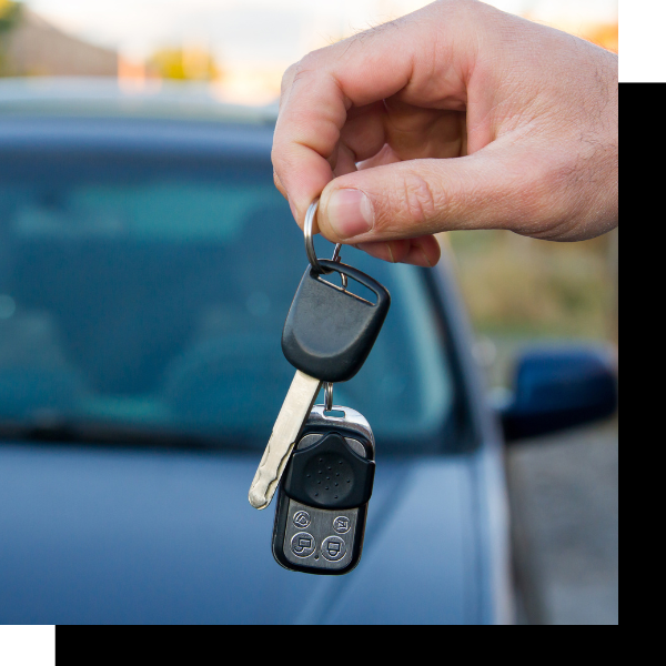 Hand holding a car key and remote in front of a blue car