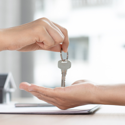 Handing over a silver key above an outstretched palm in a bright home interior