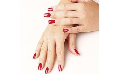 Mani con smalto rosso, appoggiate su una superficie bianca.