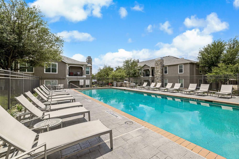 A large swimming pool surrounded by lounge chairs at Marquis at The Cascades in Tyler, TX.