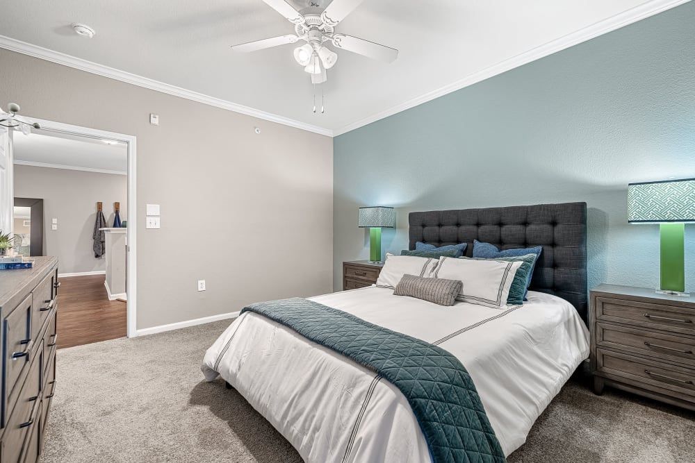 Apartment bedroom with a king-size bed and a ceiling fan at Marquis at The Cascades in Tyler, TX.