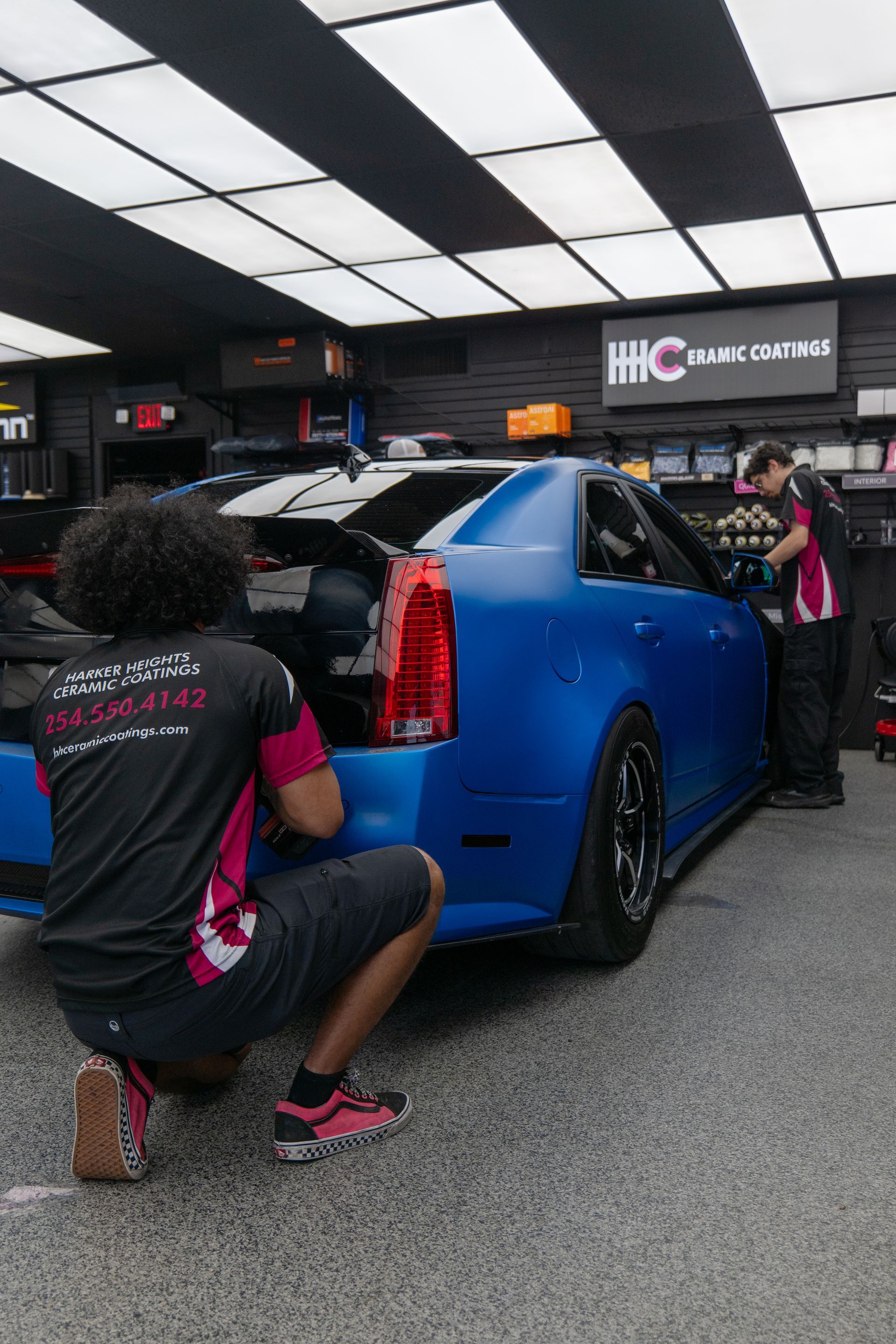 Wide view of technicians detailing and polishing a Cadillac CTS-V inside Harker Heights Ceramic Coatings located near Temple, TX.