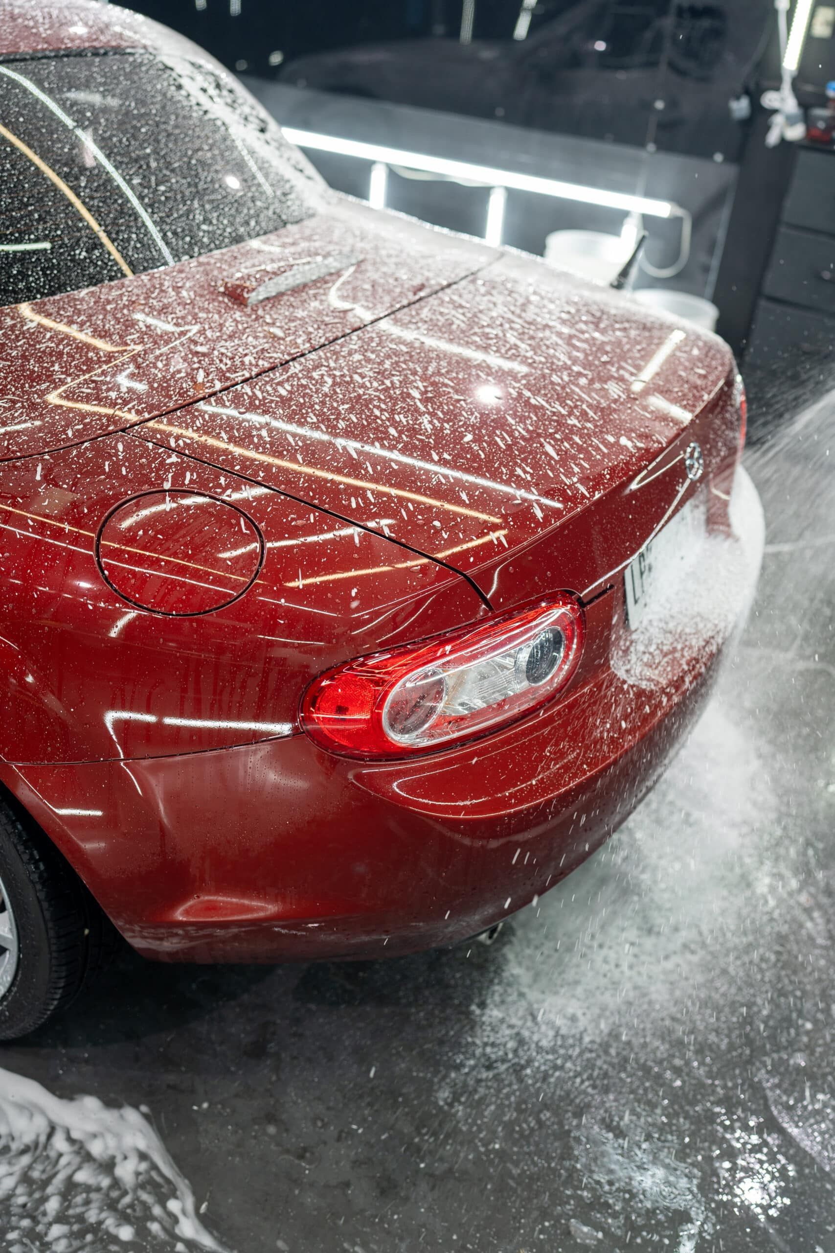 A red car is covered in snow in a parking lot