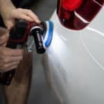 A person is polishing a car with a machine.