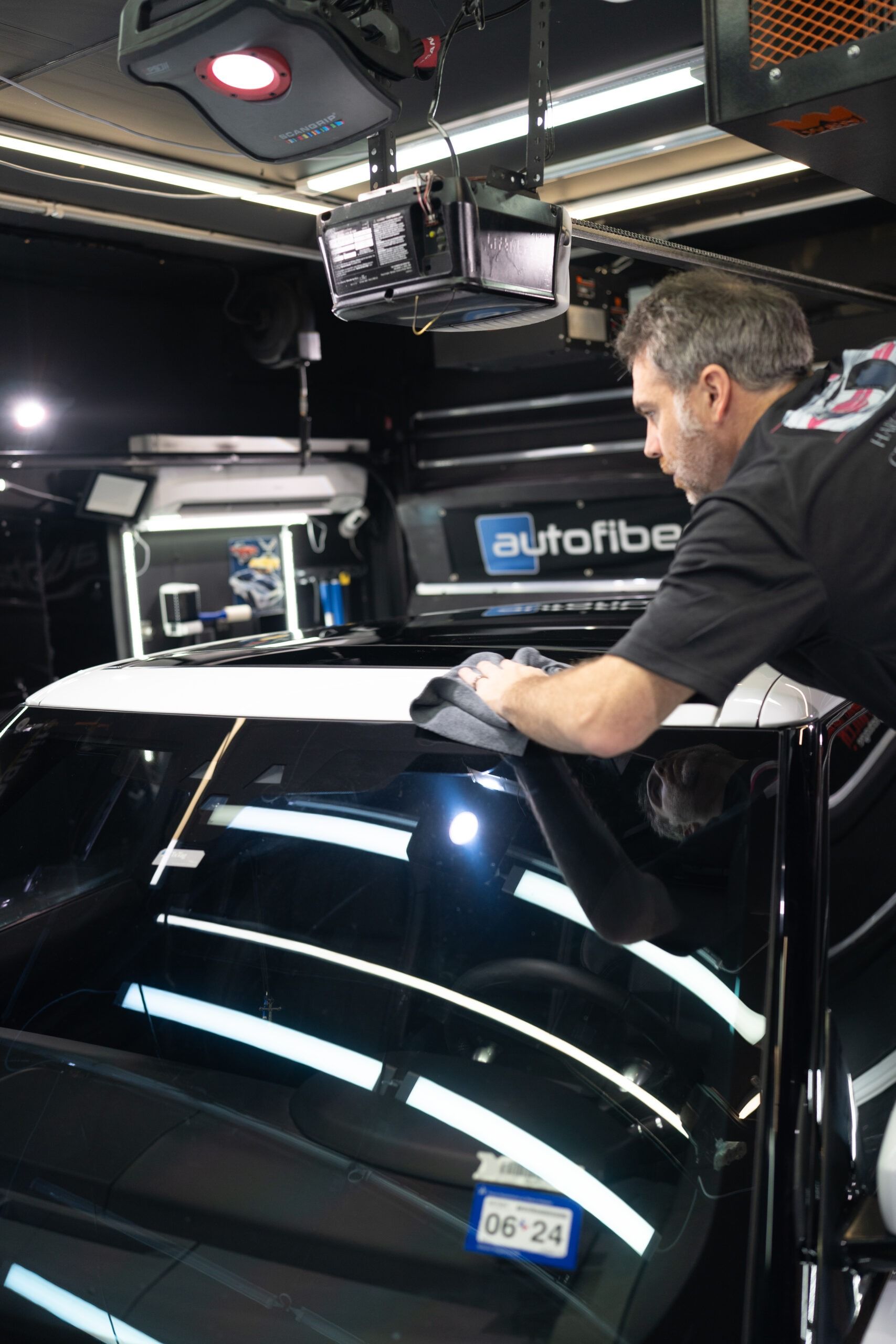 A man is working on a car with a license plate that says 06-24