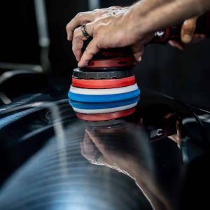A person is polishing a car with a machine.