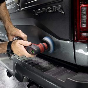 A man is polishing the back of a raptor truck.