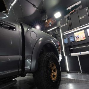 A truck is parked in a garage with its hood up.