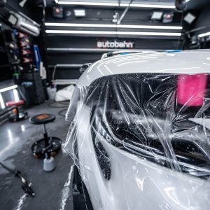 A white car is wrapped in plastic in a garage.