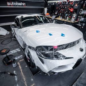 A white car is wrapped in plastic in a garage.