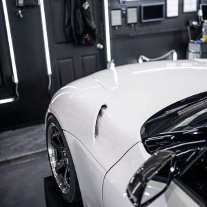 A white sports car is parked in a garage.