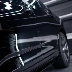 A black car is parked in a garage with the door open.
