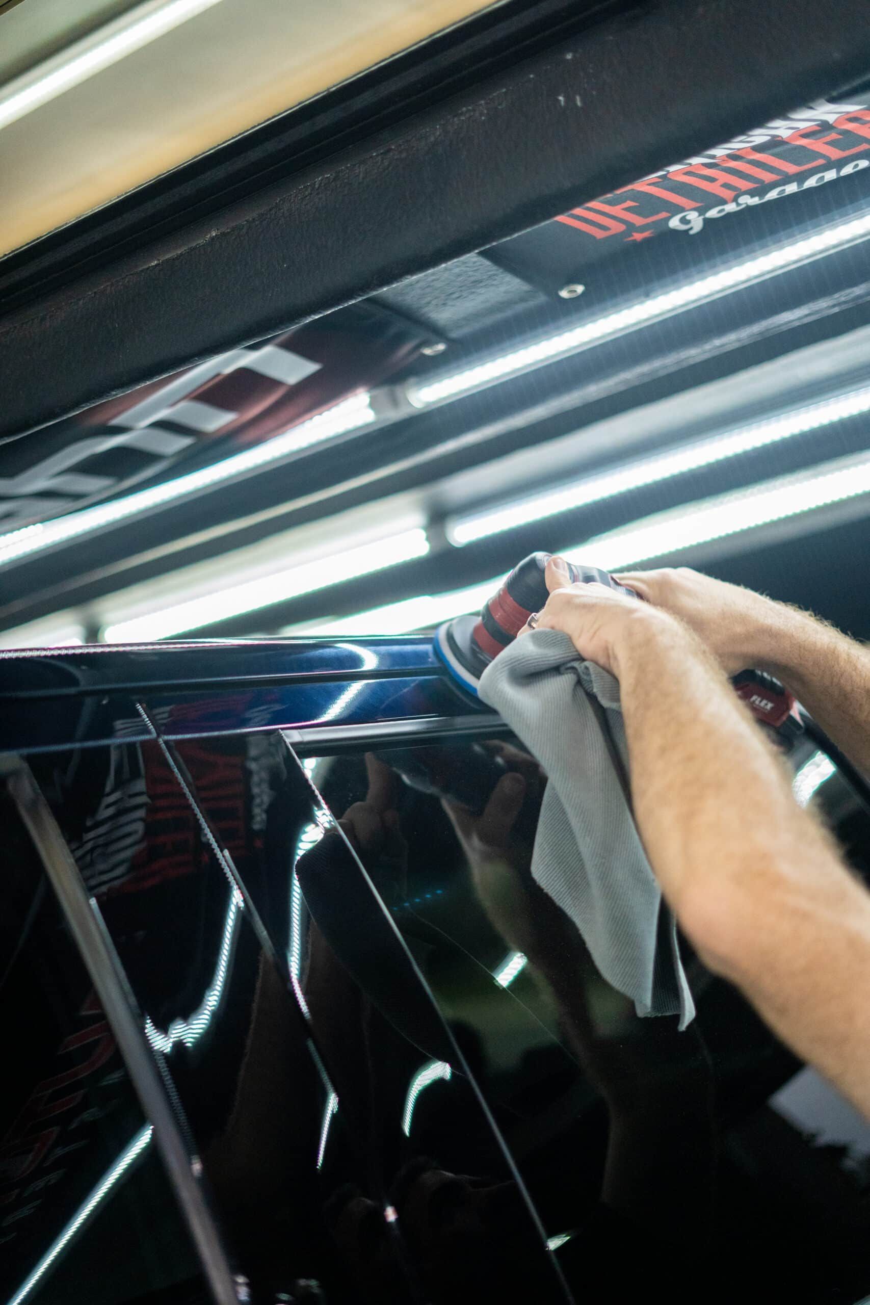 A person is polishing a car with a polisher and a towel.