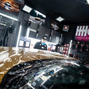 A man is standing in front of a car in a garage.