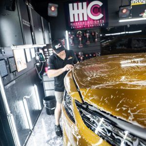 A man is wrapping a car with plastic wrap in a garage.
