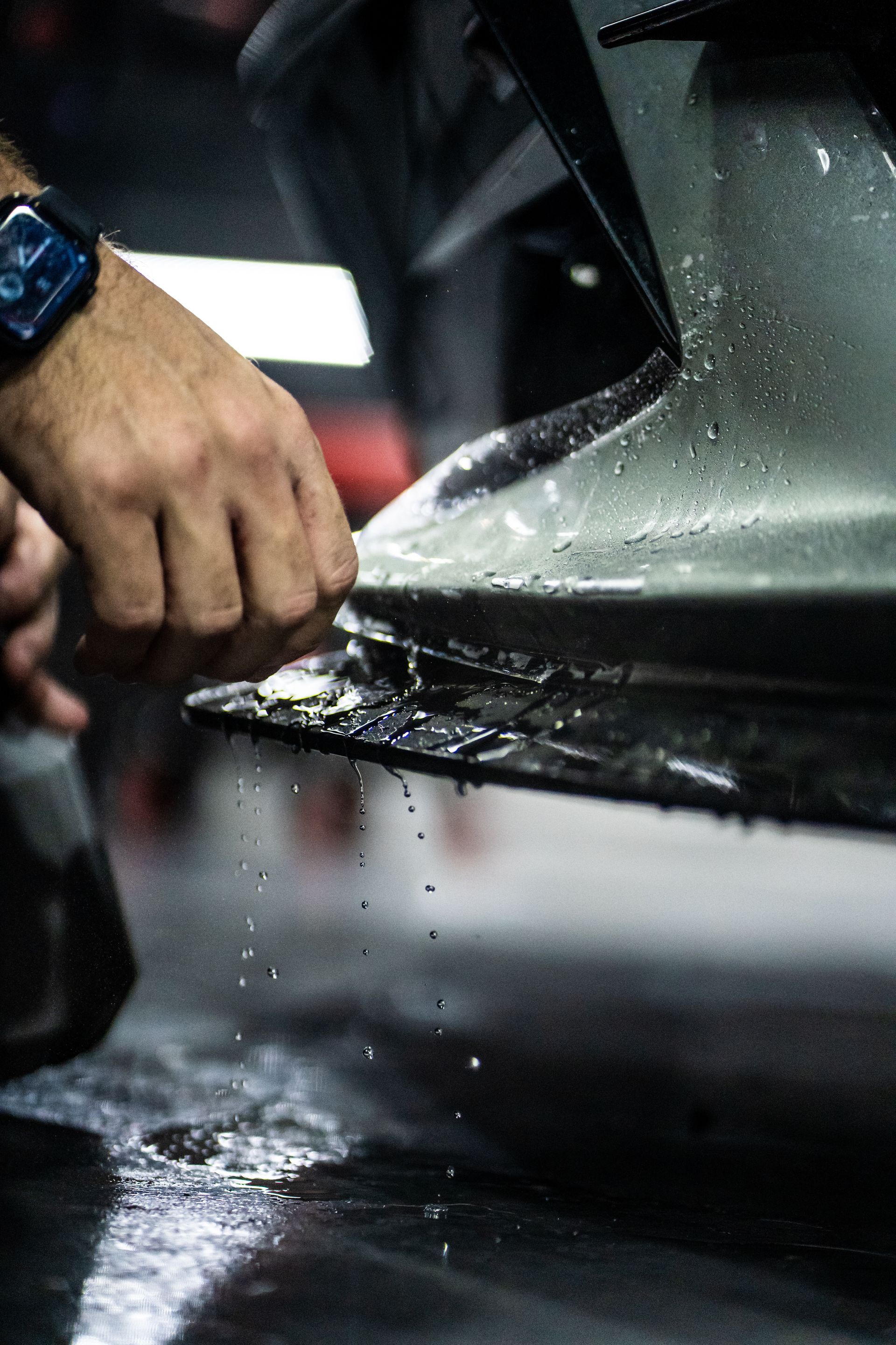 A man is applying a protective film to the side of a car.