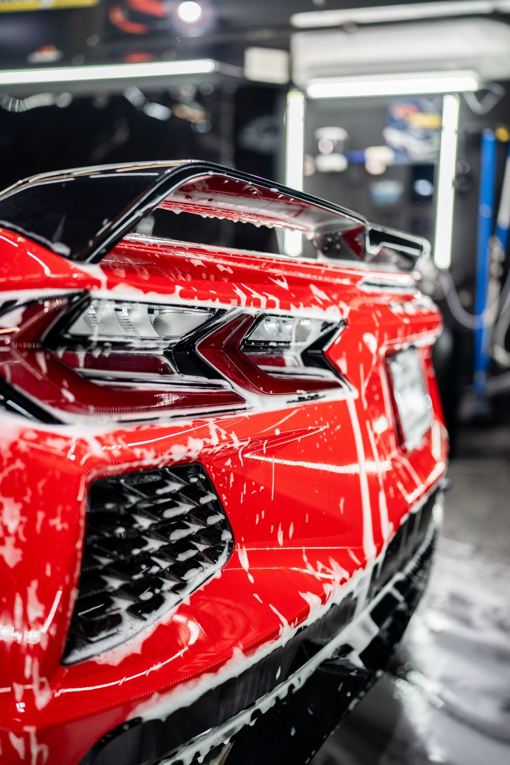 A red sports car is being washed in a car wash.