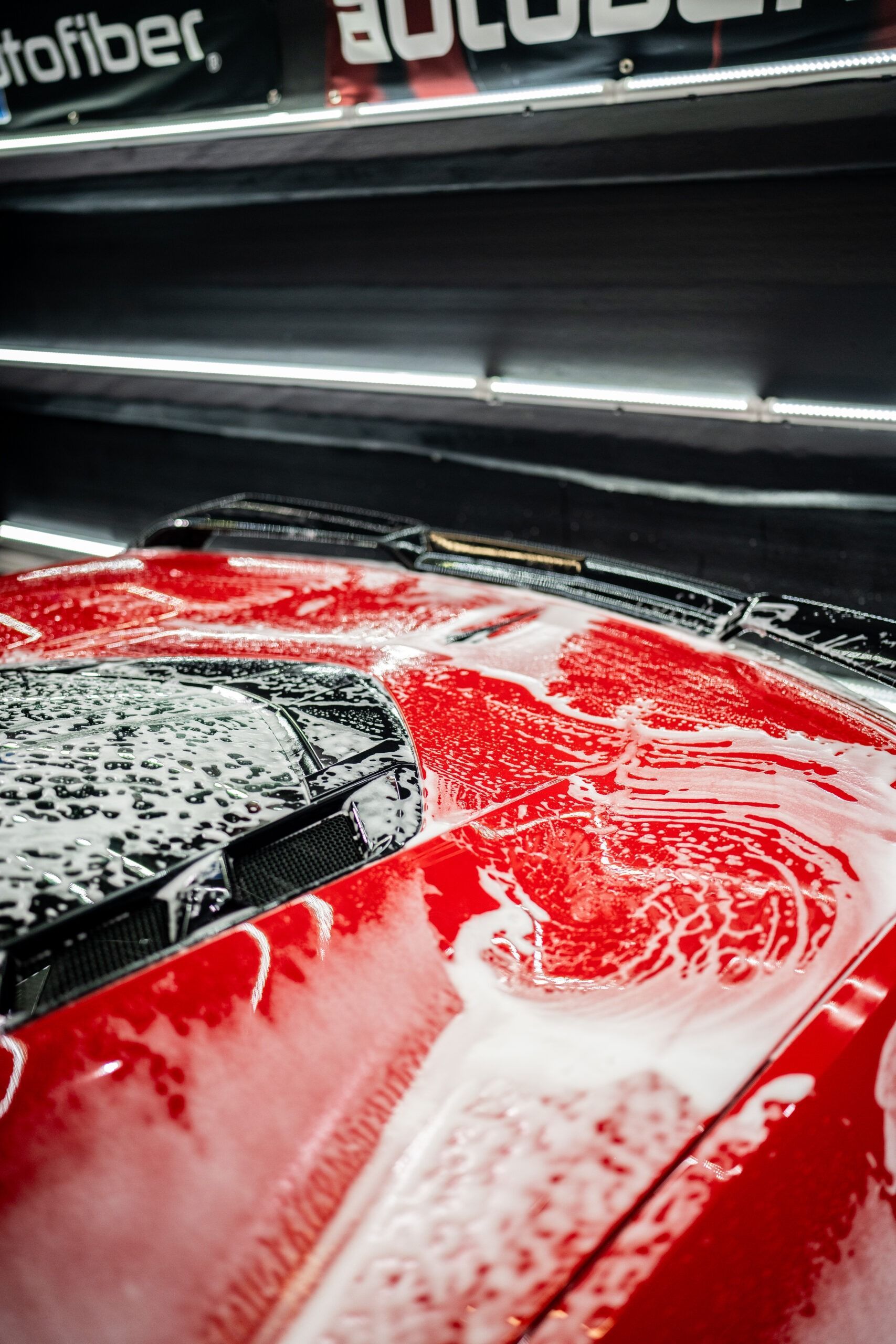 A red car is being washed in a car wash.