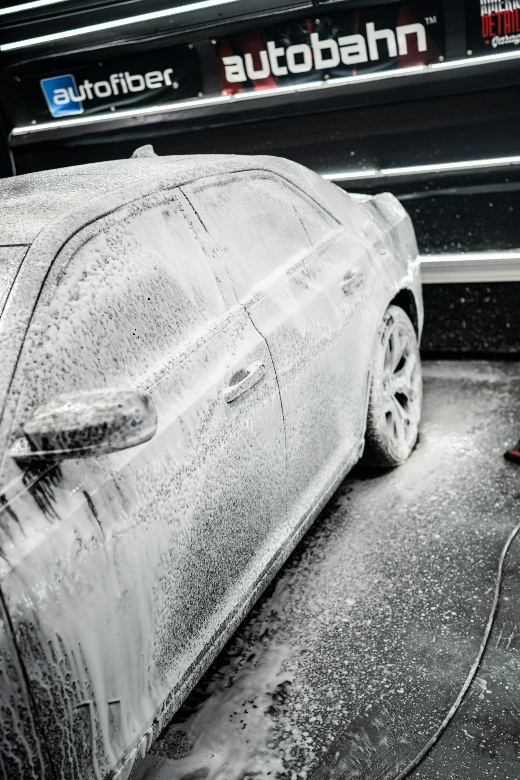 A car is covered in foam at a car wash.