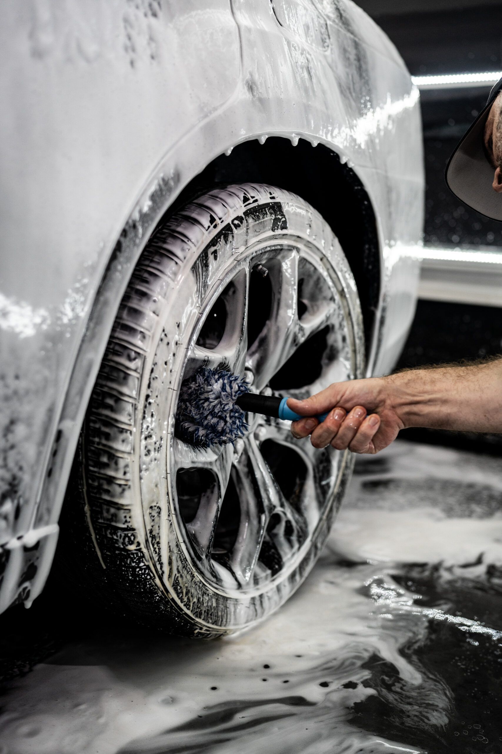 A person is cleaning a car wheel with a brush.