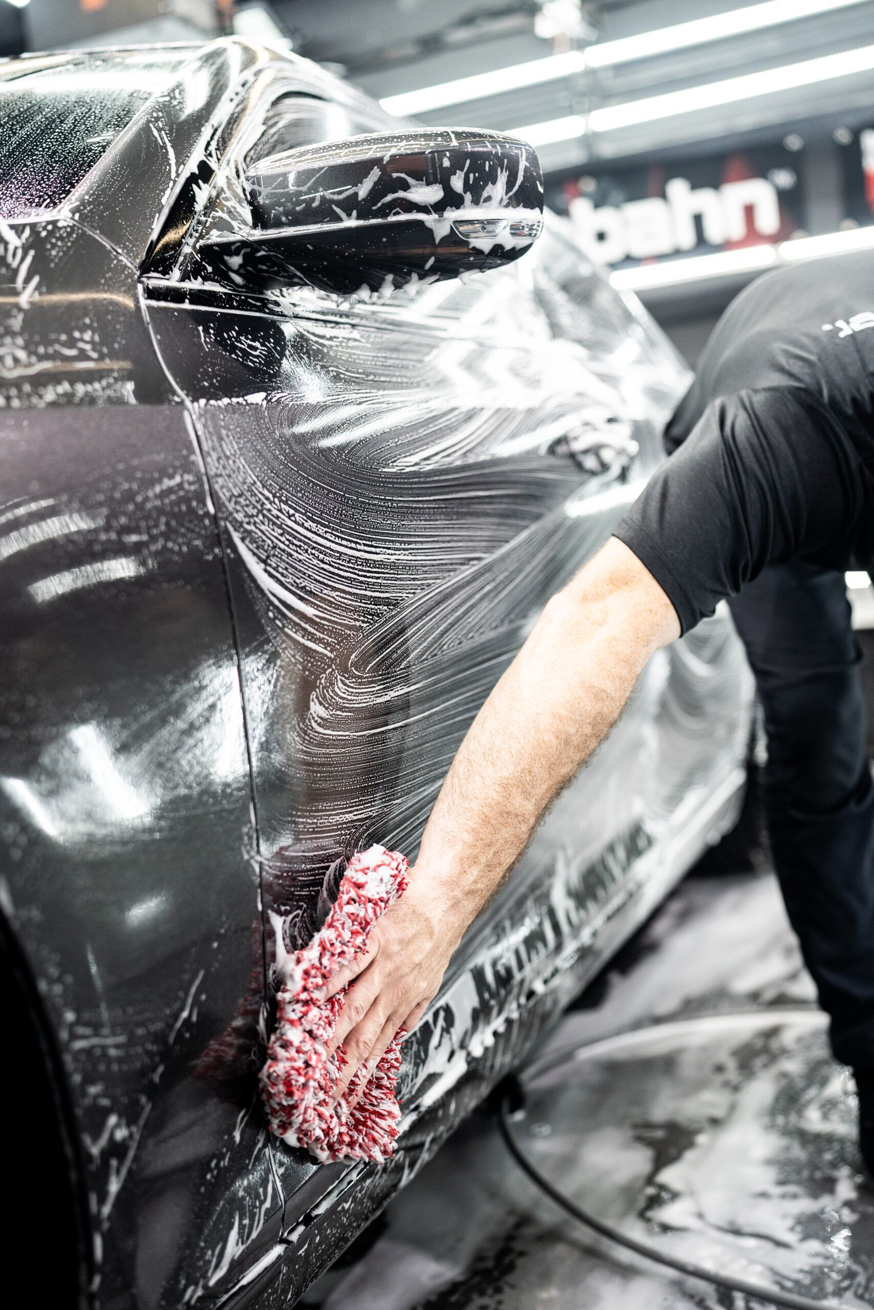 A man is washing a car with a sponge.