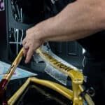 A man is working on a bicycle frame with a pair of scissors.