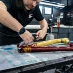 A man is working on a piece of metal on a table.