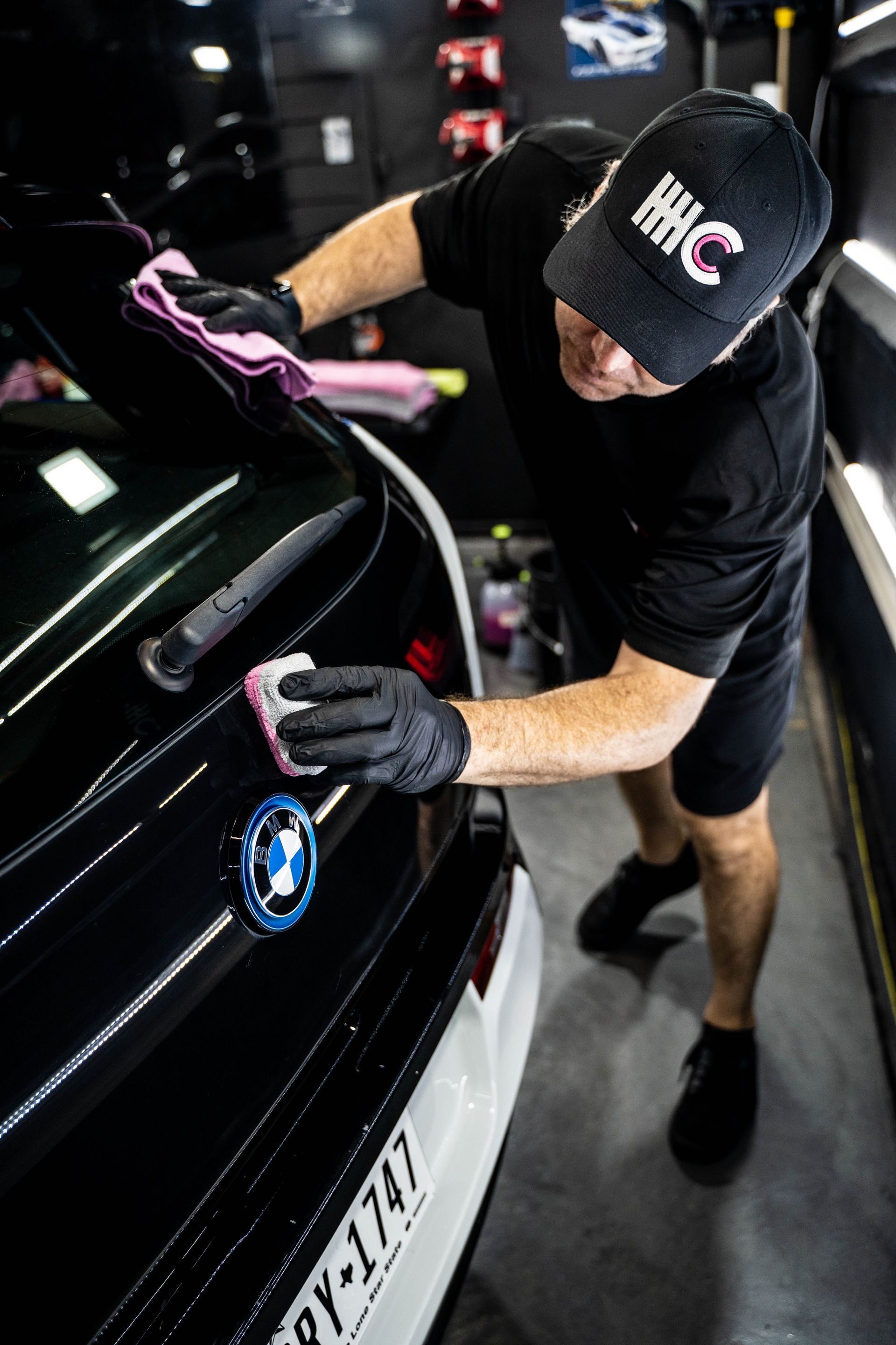A man is cleaning the back of a car with a cloth.